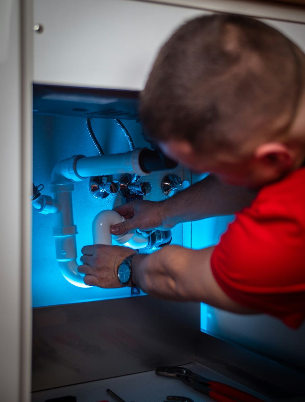 Plumber repairing under-sink pipes in Singapore